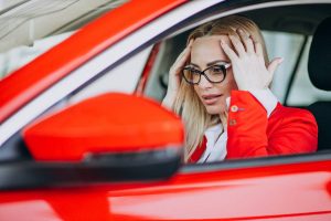 Jeune femme avec du malus dans une voiture rouge