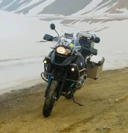 Moto BMW GS stationné sur un chemin de terre avec paysage enneigé