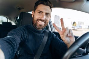 Conducteur heureux au volant de sa voiture assurée au kilomètre